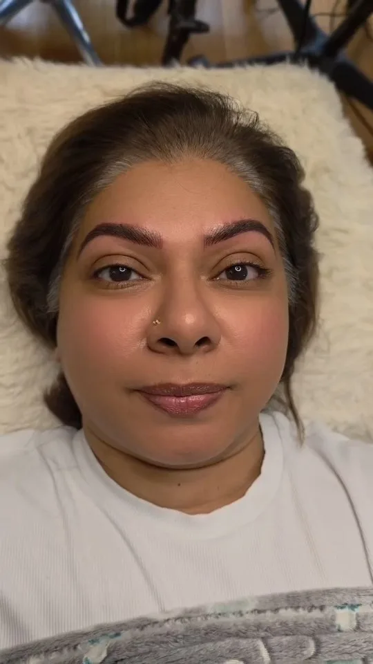 Mature client — healed natural brow result, reclined on white blanket